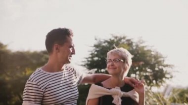 Romantik Çift birlikte dans ve birbirlerine gülümseyen güzel yaz gün batımı parkta yürüyüş yavaş rahat