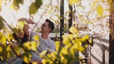 Ağır çekim Genç adam ve birlikte güzel güneşli sonbahar günde bir bankta oturmuş, eğleniyor ve gülümseyen kadın.