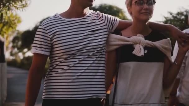 Slow motion ontspannen gelukkig man en vrouw lopen samen knuffelen elkaar en praten in een mooie zomerse zonsondergang park. — Stockvideo