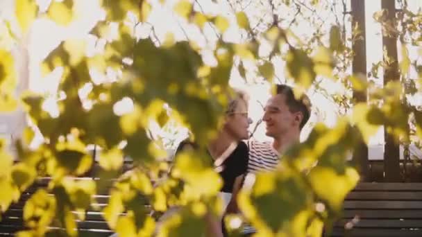 Entspanntes romantisches Paar, das in Zeitlupe eng beieinander sitzt und auf einer Bank in einem wunderschönen Park bei Sonnenuntergang plaudert. — Stockvideo