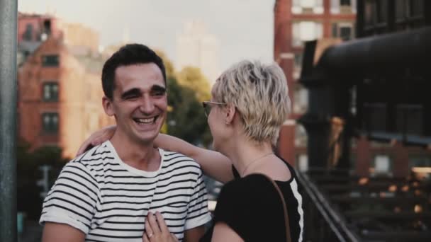 Slow motion feliz hispano hombre y europeo chica hablando y riendo juntos en un gran puente de la ciudad en verano Nueva York . — Vídeo de stock