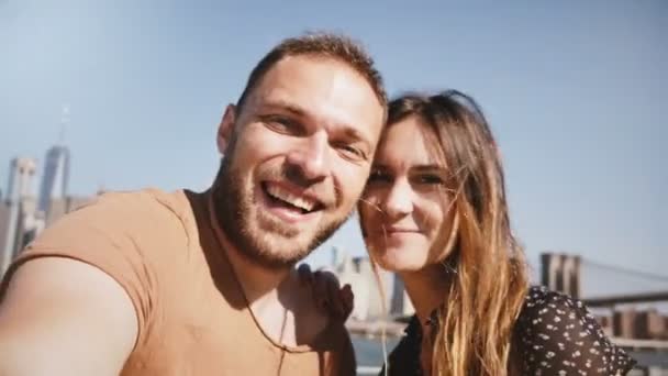 Lachende gelukkige Kaukasische jonge paar staan epische New York skyline uitzicht op Manhattan, kussen en een selfie foto maken. — Stockvideo