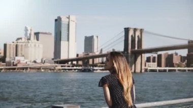 Ünlü New York skyline zevk saç uçan ile mutlu gülümseyen Avrupa kadın görünümünü ve Brooklyn Köprüsü'nün görünümü kaydırma.