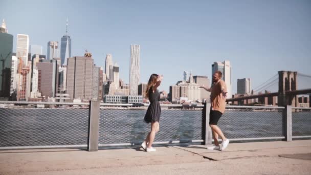 Gelukkig Europees meisje aan haar vriendje, knuffelen en praten op zonnige weergave van Manhattan in New York City slow motion. — Stockvideo
