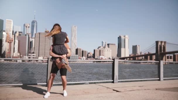 Счастливый белый мужчина встречает свою девушку, обнимает и улыбается солнечному горизонту Манхэттена в замедленной съемке в Нью-Йорке . — стоковое видео