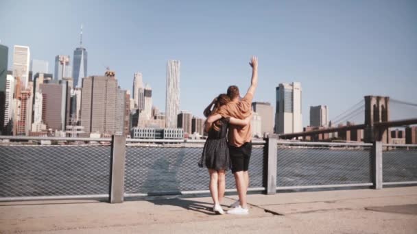 Gelukkig Europese toeristische paar staan knuffelen, armen verhoogd genieten van epische Manhattan weergave in slow-motion van New York, Verenigde Staten. — Stockvideo