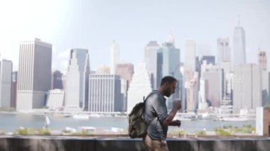 Mutlu başarılı Avrupa serbest çalışan kahve ve smartphone ile New York'ta epik Manhattan siluetinin boyunca yürüyüş.