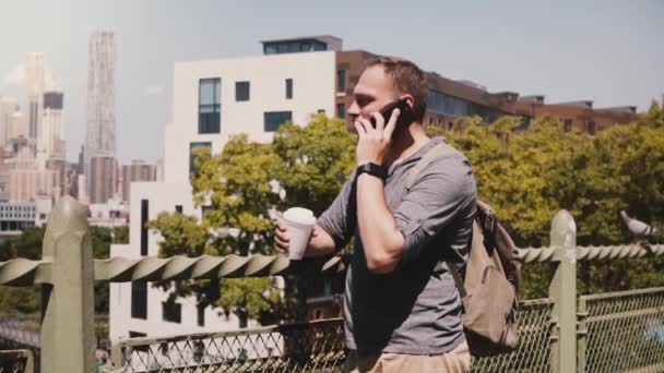 Αυτοπεποίθηση νεαρός ευτυχής επιχειρηματίας Καυκάσιος μιλώντας στο τηλέφωνο με καφέ κοντά σε πόλη της Νέας Υόρκης Πανόραμα αργή κίνηση. — Αρχείο Βίντεο