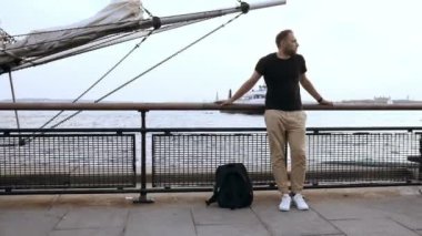 Yakışıklı delikanlı ile sırt çantası ayakta burundan yakınındaki rıhtımda, motorlu tekne kıyıya geliyor.