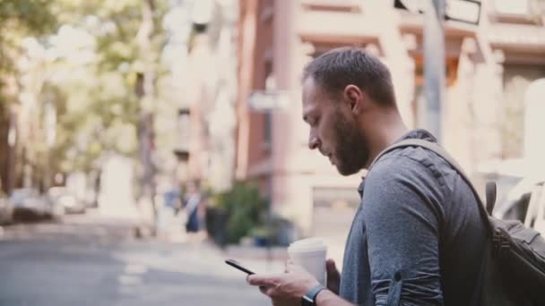 Feliz trabajador independiente europeo exitoso con café utilizando la aplicación de mensajería smartphone, mirando a su alrededor y alejándose . — Vídeo de stock