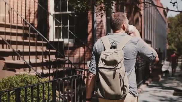 Joven turista masculino caucásico relajado con mochila caminando por la soleada calle de la ciudad de verano en Nueva York bebiendo café . — Vídeos de Stock