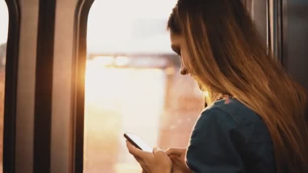 Hermosa mujer tomando un metro en Chicago, EE.UU. Atractiva hembra usando smartphone mientras el tren se mueve al atardecer . — Vídeo de stock