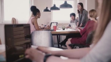 Dizüstü bilgisayarda yazarak tanınmaz kız. Modern çok ırklı loft ofiste içinde belgili tanımlık geçmiş tabloda beyin fırtınası.