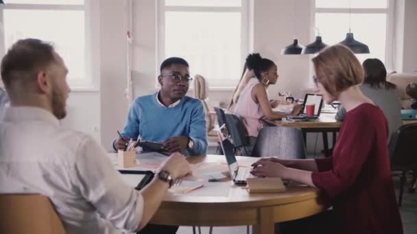 Avrupa kadın patron çalışanlara, türleri tablosu tarafından laptop kılavuzları verir. Office Toplantısında çok ırklı ekip çalışması. — Stok video