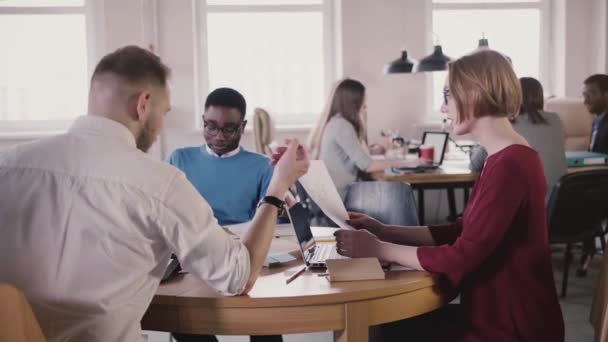 La jefa de equipo explica la hoja de diagrama al empleado masculino. Reunión del equipo multiétnico en un moderno loft en un lugar de trabajo saludable . — Vídeo de stock