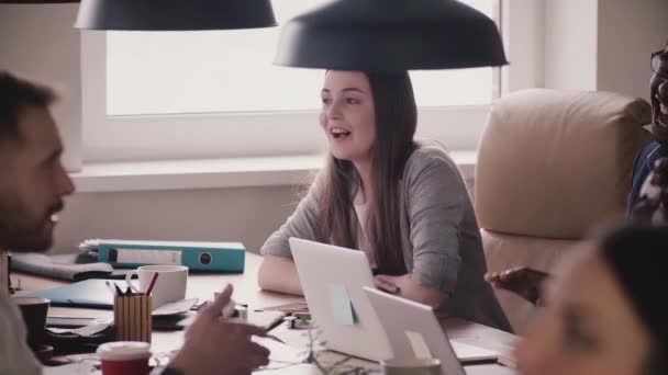 Щасливі багатоетнічні офісні працівники сміються за столом під час командної ділової зустрічі на сучасному здоровому робочому місці . — стокове відео