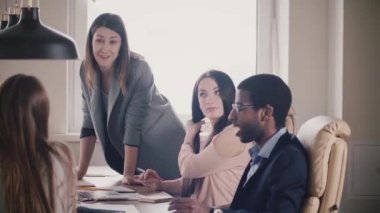 Başarılı çekici işkadını çok ırklı takım teşvik eder. Ofis Toplantı tablo tarafından önde gelen genç kadın patron.