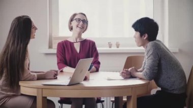 2 güzel pozitif beyaz kızlar Japon bir iş görüşmesi modern sağlıklı ofis tabloda tarafından Adamlakonuşmak.