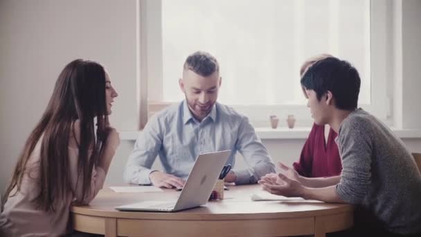 Glücklich multiethnische junge Geschäftsleute Brainstorming zusammen am Tisch in freundlicher Atmosphäre von gesunden Arbeitsplatz. — Stockvideo