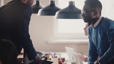 Mutlu Afro-Amerikan çalışan office masaya oturur, patron el sallar gülümseyerek, top ağır çekim yakın çekim ile oynamak.