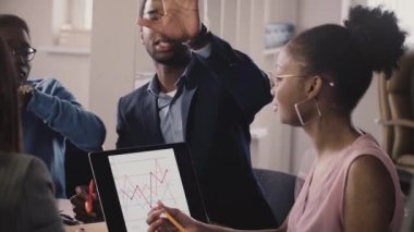 Afro-Amerikan iş adamları konuşmak, hareketleri göstermek ve dizüstü diyagramları arayan office toplantıda, iletişim.