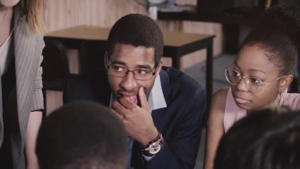 Des hommes d'affaires afro-américains font du remue-méninges autour de la table, écoutent une dirigeante européenne lors d'une réunion de bureau multiethnique 