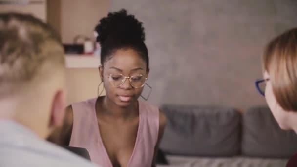 Beautiful African American businesswoman sits down by the table, smiles at multiethnic colleagues at office meeting. — Stock Video