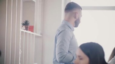 Kamera genç beyaz erkek patron mutlu çok ırklı meslektaşları için tablo yavaş hareket tarafından konuşmak için geliyor izler.