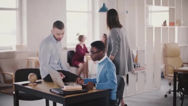 Dos colegas multiétnicos casuales colaboran en un lugar de trabajo moderno y saludable, una jefa caucásica confiada caminando . — Vídeo de stock