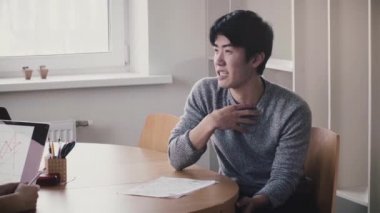 Modern trendy hafif ofis iş görüşmesine gülümseyen tablo tarafından konuşan genç yakışıklı mutlu Japon adam.