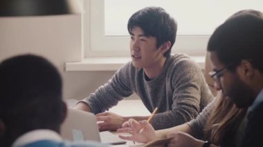 Dinleme ve çok ırklı office toplantıda gülümseyen yakın çekim mutlu emin Japon Genç profesyonel iş adamı.