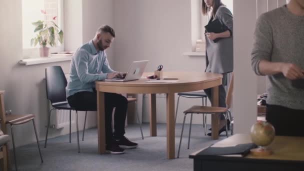 Young female boss in formal clothes comes up, sits down by male employee working with laptop to help in modern office. — Stock Video