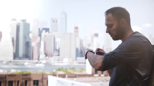 Heureux entrepreneur masculin confiant utilisant bracelet intelligent debout à Manhattan panorama paysage urbain incroyable, New York City . — Video