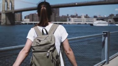 Güzel genç turist kadın sırt çantası ile silah yakınındaki New York'taki Manhattan skyline panorama sevinçle açık yükseltir