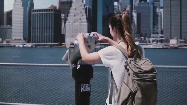 Jonge reiziger meisje kijkt door de verrekijker telescoop munt op de geweldige skyline van de stad van Manhattan, New York slow motion. — Stockvideo