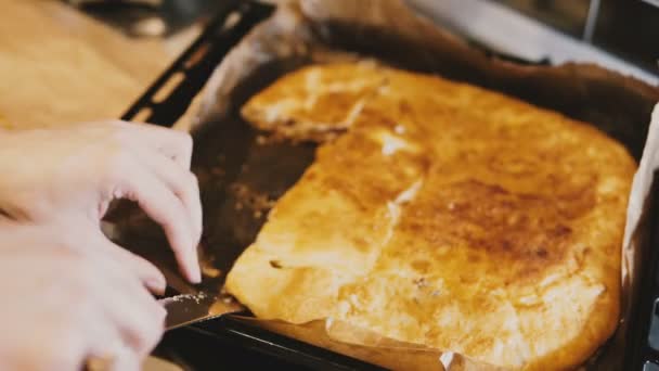 Vista de cerca de las manos de cocinera tratando de tomar trozos pegajosos de pastel casero de la bandeja de la cocina con un cuchillo . — Vídeos de Stock