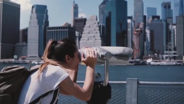 Happy female traveler looks through a tower viewer at epic sunny cityscape skyline of Manhattan, New York slow motion. — Stock Video