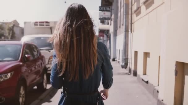 Kamera podąża młody student dziewczyna w niebieskiej sukience z długimi włosami wiejący wiatr spaceru wzdłuż ulicy zwolnionym tempie. — Wideo stockowe