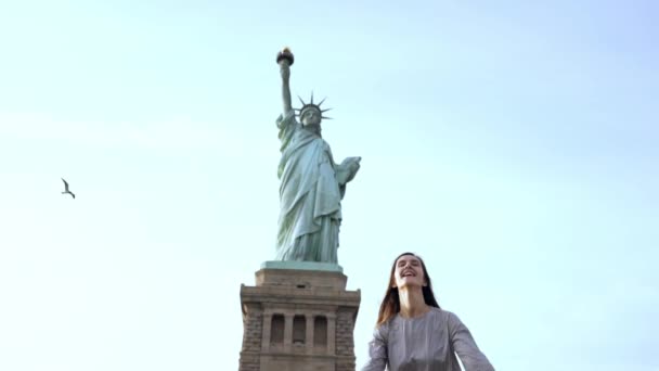 Successful Caucasian female student jumping high with joy and cheer celebrating success at Statue of Liberty slow motion — Stock Video
