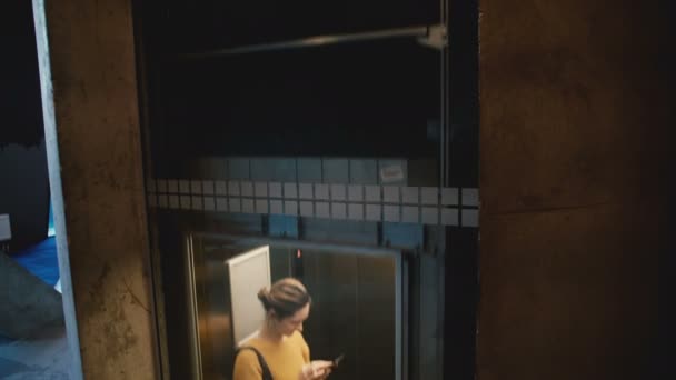 Joven mujer sonriente feliz montando ascensor con pared de vidrio transparente, saliendo con la aplicación de compras de teléfonos inteligentes en línea . — Vídeos de Stock
