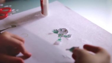 Kağıt, tutkal bir tablo ve komik karakter şekilleri oluşturma pembe kazaklı kız yakın çekim shot eller.