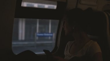 Trende, seyahat ederken smartphone kullanarak güzel beyaz işkadını penceresine bakarak iletileri, yazarak.