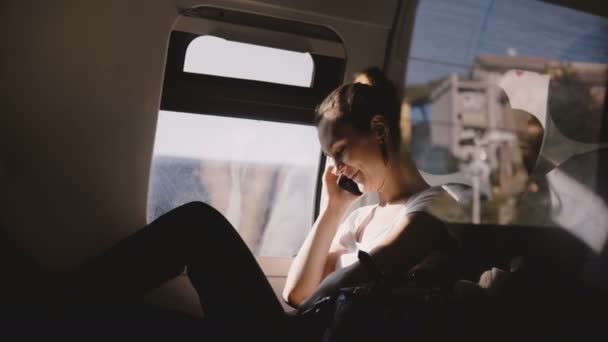 행복 한 아름 다운 백인 여자 웃 고, 전화 통화 및 현대 기차 창이 자리에 여행 하는 동안 끊. — 비디오