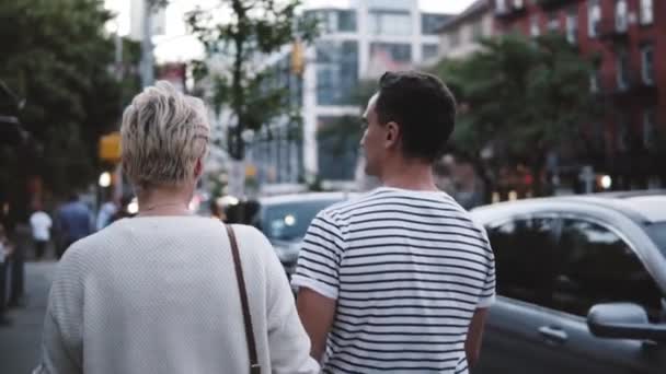 Vista trasera en cámara lenta pacífico hombre y mujer caminan juntos tomados de la mano disfrutando de las vistas urbanas nocturnas de la ciudad de Nueva York . — Vídeo de stock