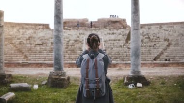 Ostia İtalya Antik Amfitiyatro ayağı smartphone fotoğraf çekici sırt çantası ile Kafkas turist kızın arkadan görünüm