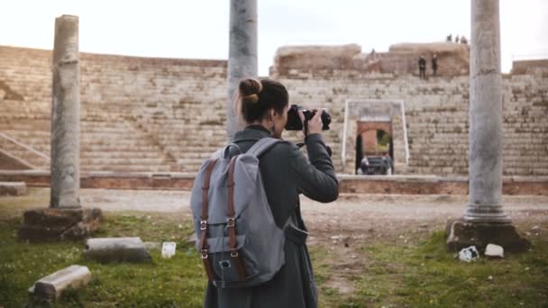 Kembali melihat gadis perjalanan blogger profesional dengan kamera mengambil foto pilar amfiteater kuno di Ostia, Italia . — Stok Video