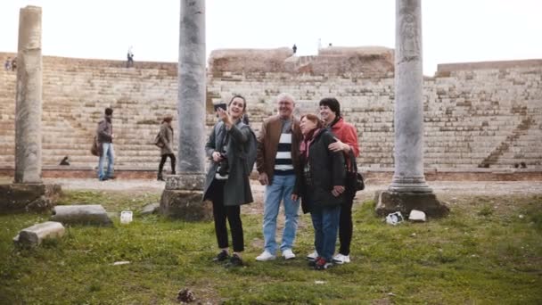 Lachende senior familie en jonge vrouw toeristen zwaaien op video-oproep aan familie bij oude amfitheater ruïnes in Ostia, Italië. — Stockvideo