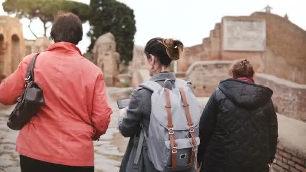 Glada lyckliga blandad ålder Europeiska turist kvinnor utforska gamla historiska ruinerna i Ostia, Italien, titta på smartphone foton. — Stockvideo