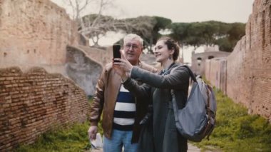 Heyecanlı mutlu komuta sizde ve gülümseyen Avrupa Genç kadın tatil gezisinde Ostia, İtalya için eski ruins yakınındaki selfie alarak.