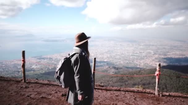 Zijaanzicht van jonge mooie vrouwelijke toerist met rugzak wandelen naar beneden van de Vesuvius vulkaan genieten van uitzicht op Napels. — Stockvideo